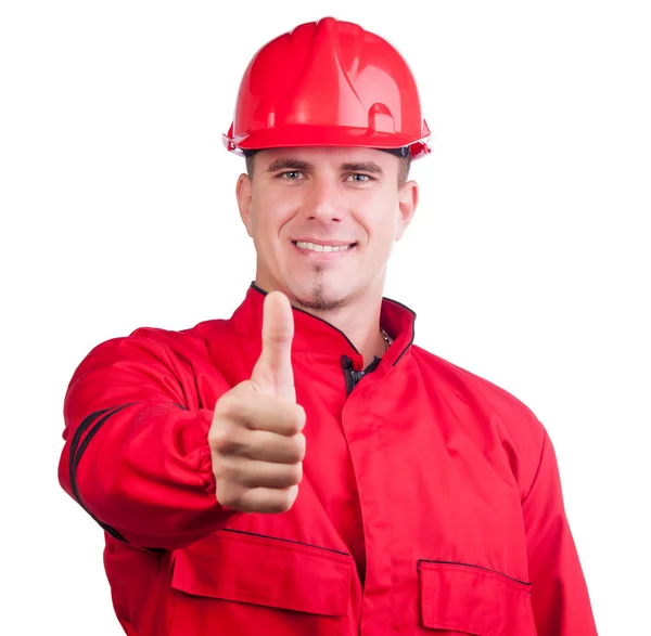 Giovane pompiere sorridente con cappello duro e in piena uniforme mostrando i pollici in alto isolato su bianco . — Foto Stock