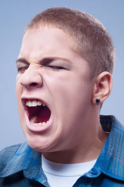 Portrait of young teenage boy screaming isolated on gray — Stock Photo, Image