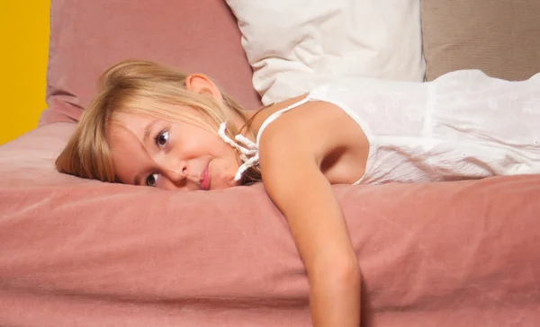 Linda menina entediada deitada na cama em seu quarto — Fotografia de Stock