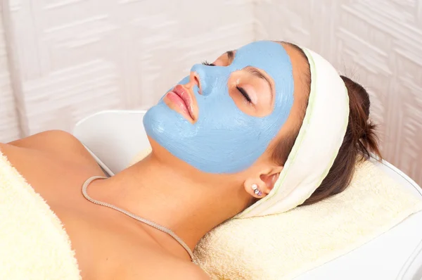 Vacker ung kvinna ligga på massagebänk med naturlig ansiktsmask i ansiktet — Stockfoto