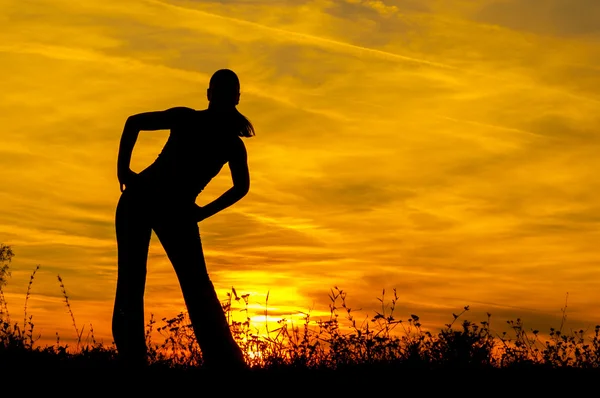 La silueta de la muchacha delgada que se extiende en la naturaleza al amanecer — Foto de Stock