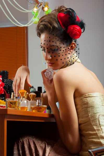 Beautiful old fashioned lady plays with perfumes in front of the mirror — Stock Photo, Image