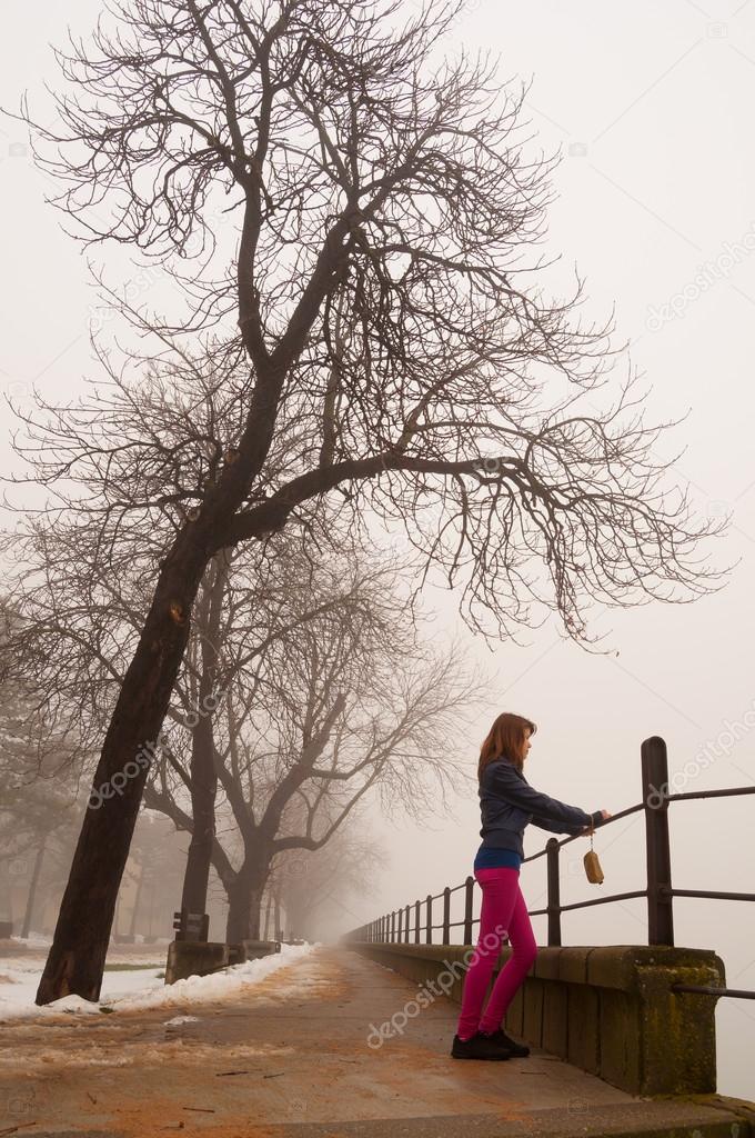 Lonely teenage girl watching the mist on cold winter day