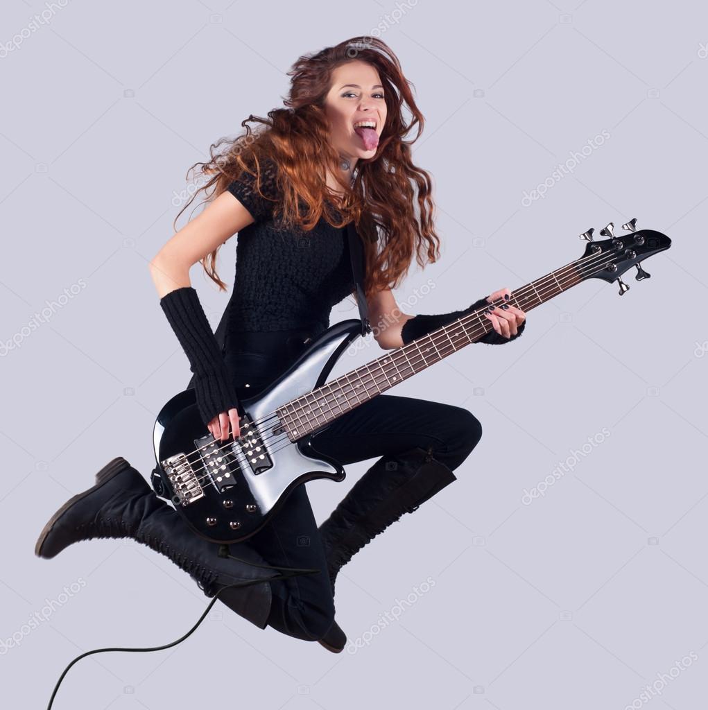 Beautiful smiling girl with bass guitar jumping high in the air — Stock