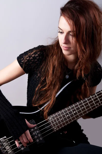 Beautiful girl in black plays black bass guitar — Stock Photo, Image