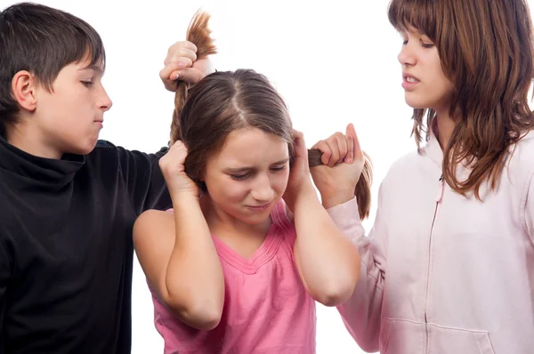 Tiener en tienermeisje trekken haren van kleinere tienermeisje — Stockfoto