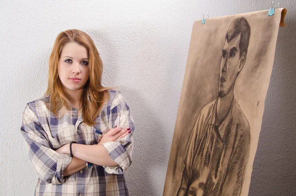 Unga kvinnliga artist poserar bredvid hennes konstverk. — Stockfoto