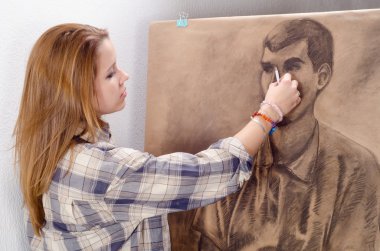 Young female artist drawing man portrait in her art studio. clipart