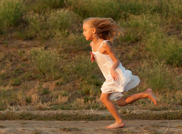 Cute little girl in white dress running on sunny spring day — Stock Photo, Image