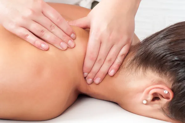 Jovem mulher recebendo massagem no salão de massagem Fotos De Bancos De Imagens