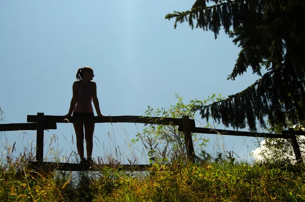 Silhouette eines Mädchens, das auf dem Holzzaun steht — Stockfoto