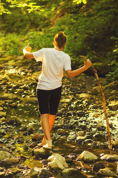 Teenage girl walking on the stones in the stream — Stock Photo, Image