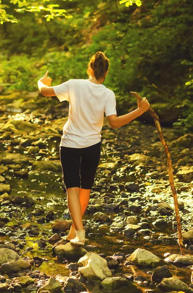 Tienermeisje lopen op de stenen in de stream — Stockfoto