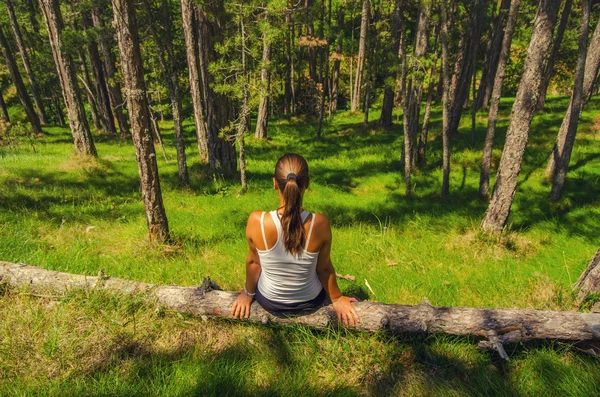 Młoda kobieta siedząca w lesie — Zdjęcie stockowe