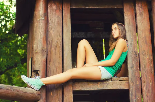 Teenage girl sitting in the wooden house — Stock Photo, Image