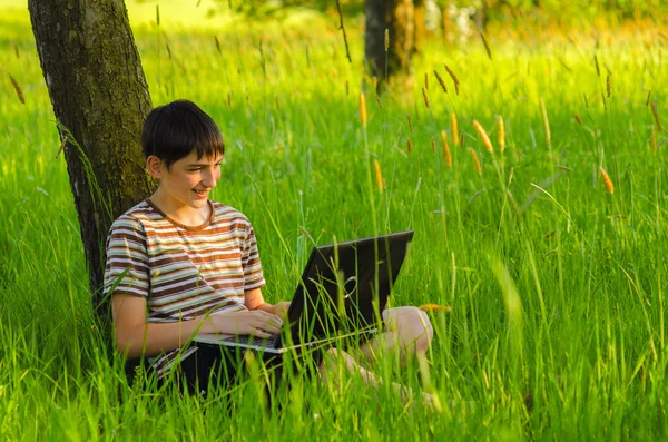 Adolescente niño trabajando en portátil en la naturaleza — Foto de Stock