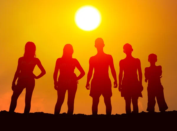 Silhouetten van jongens en meisjes op het strand — Stockfoto