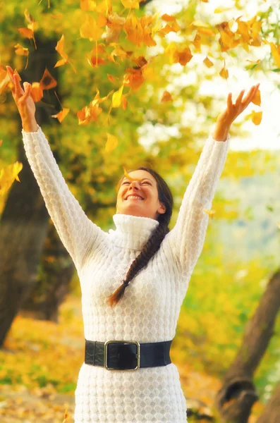 Meisje gooien herfst bladeren in de lucht — Stockfoto