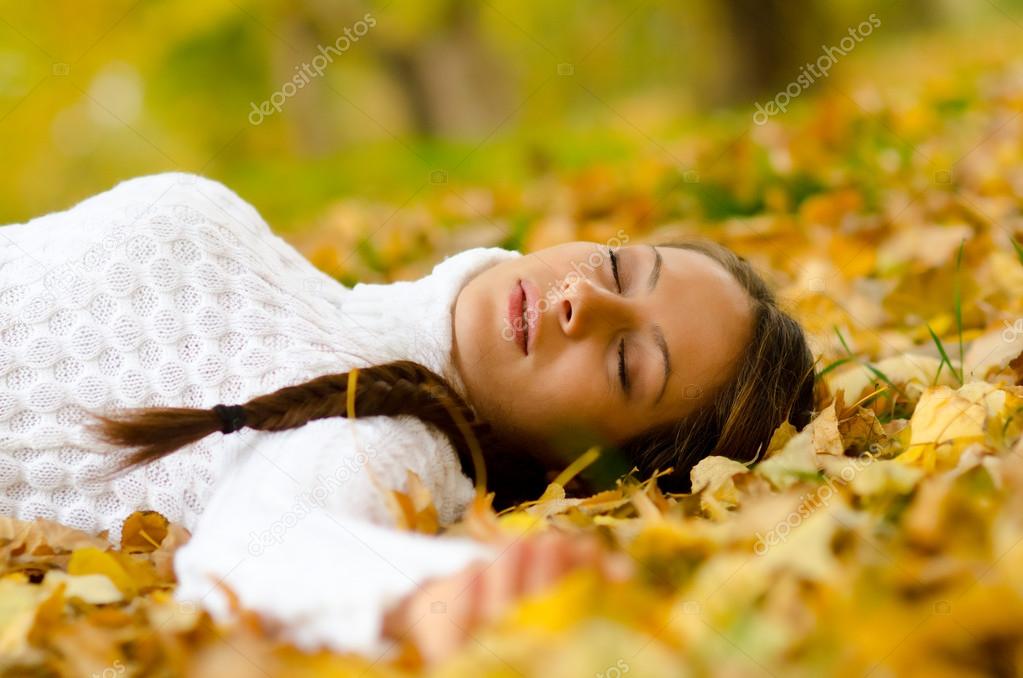 Beautiful girl lying on autumn leaves