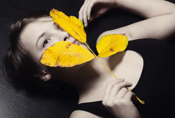 Girl on the floor holding autumn leaf — Stock Photo, Image