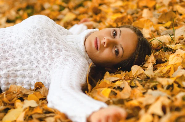 Vacker flicka liggande på hösten lämnar — Stockfoto