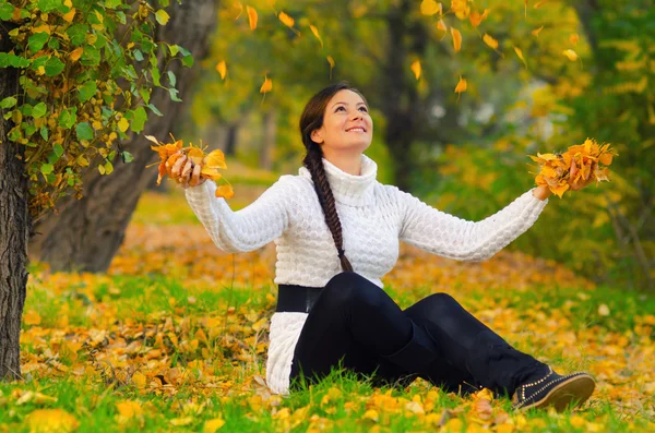 Chica lanzando hojas secas de otoño en el aire — Foto de Stock