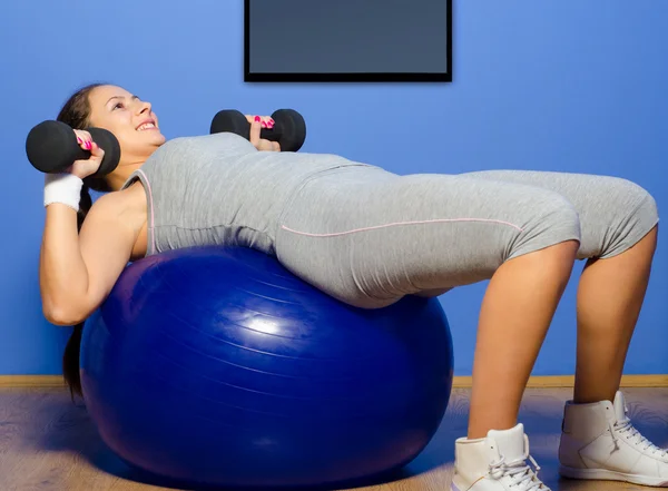 Smiling girl exercising with dumbbells — Stock Photo, Image