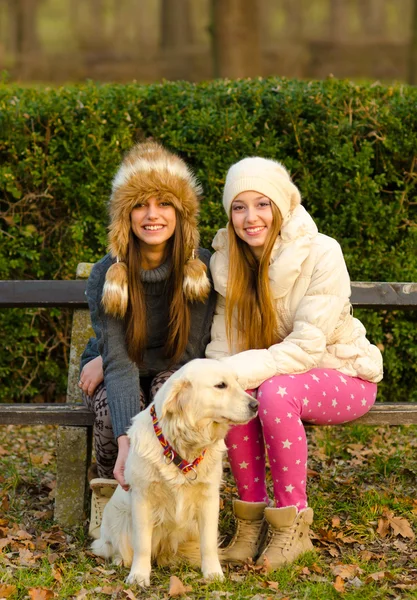 Dos hermosas chicas y un perro en el parque —  Fotos de Stock