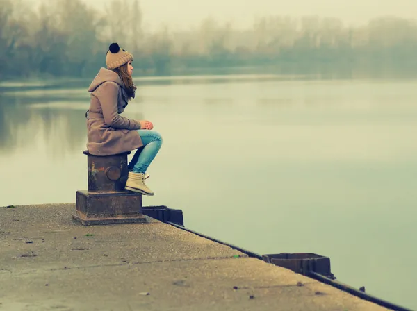 Lonely teenage girl sitting on the dock — Stock Photo, Image