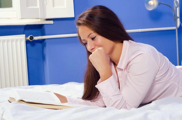 Красива дівчина читає книгу в ліжку — стокове фото