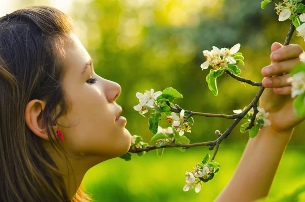 Chica oliendo flores en el huerto — Foto de Stock