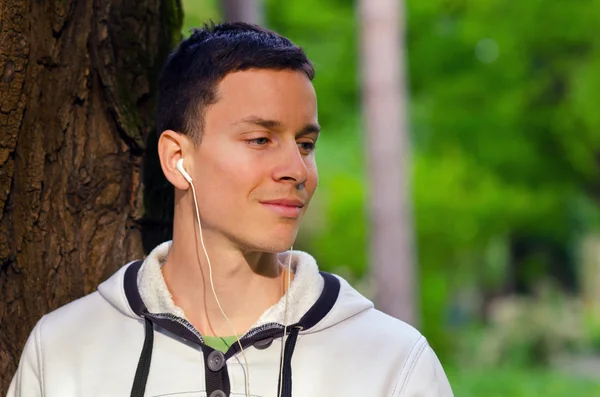 Jonge man luisteren naar de muziek in het park — Stok fotoğraf