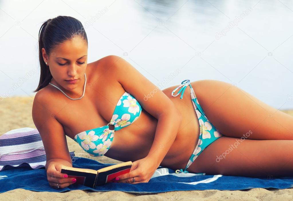 Beautiful girl reading book on the beach