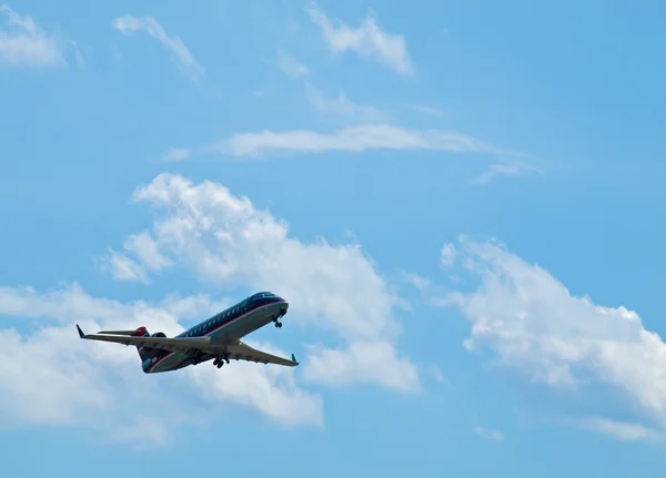 Un avion de ligne commercial décollant dans un ciel bleu partiellement nuageux — Photo