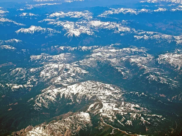 Vista de un paisaje montañoso cubierto de nieve desde un avión — Foto de Stock