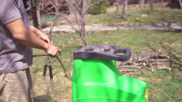 Homem colocando galhos de árvore em triturador de jardim — Vídeo de Stock