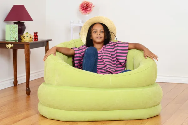 Black child relaxing in green chair — Stock Photo, Image