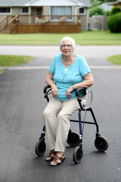 Müde Seniorin sitzt auf Rollator — Stockfoto