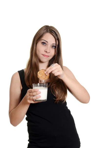 Teen girl with cookie dunked in milk — Stock Photo, Image