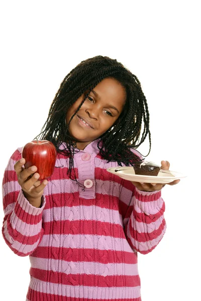 Little girl choosing between cupake and apple — Stock Photo, Image