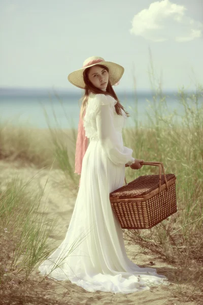 Donna in spiaggia con cestino da picnic — Foto Stock