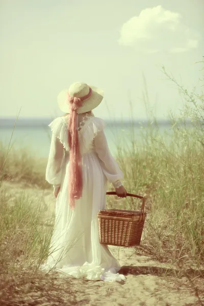 Mulher vintage na praia com cesta de piquenique — Fotografia de Stock