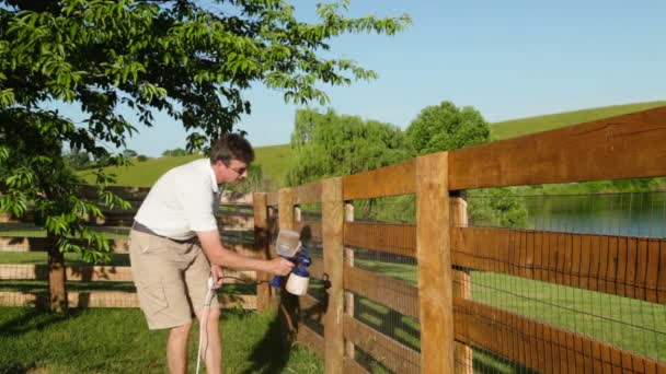 Man staining wooden fence — Stock Video