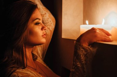 Aromaterapi. İç çamaşırlı seksi bir esmer yatmadan önce mumları söndürür. Sevgililer Günü 'nde romantik bir ortam