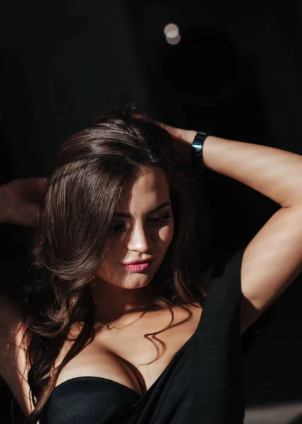 Portrait d'une brune sexy en robe noire sur fond sombre. fille enlève sa robe lentement dans la chambre — Photo