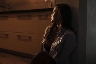 Erkek gömleği giymiş seksi bir kız mutfakta sevgilisini bekliyor.