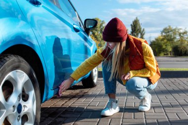 Genç bir kadın, şoför, yıkadıktan sonra mikrofiber bezle araba silmek, araba yıkamak. self-servis taşıma, bakım konsepti. Araba yıkama