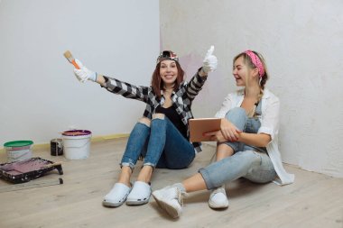 İç mekan. İki tatlı kız tasarımcı ve ressam evde tamirat yapıyor. Dekoratörlerden oluşan bir ekip.