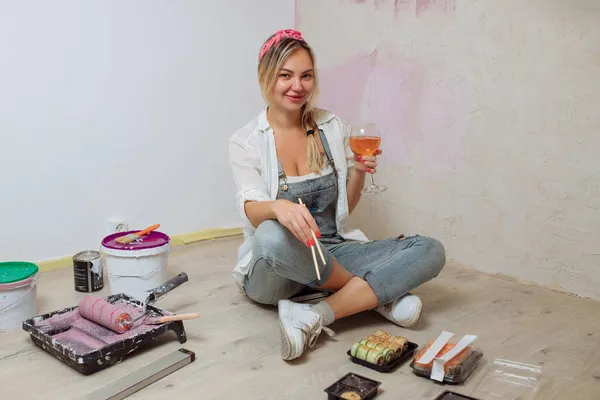 Sexy chica diseñadora come sushi en el sitio de construcción. pintor tiene almuerzo después del trabajo.Concepto de diseño de interiores y reparación de habitaciones — Foto de Stock