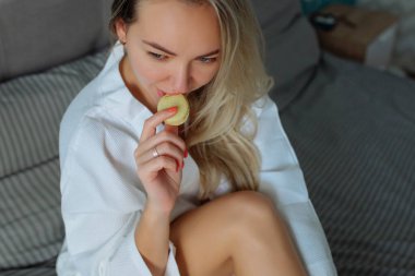 Kapalı mekanda kahvaltı. Beyaz bornozlu seksi bir kız badem kurabiyesi yiyor. Otel tatilleri